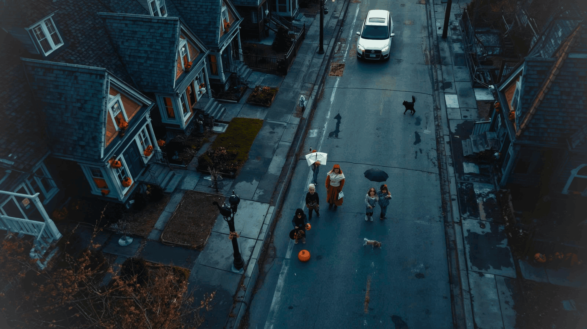 Halloween night street view with trick-or-treaters and cars